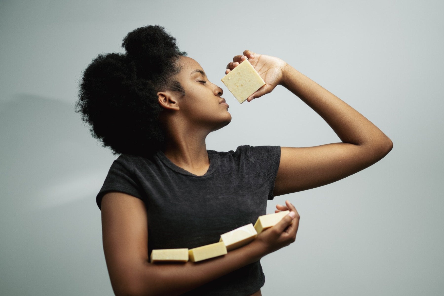 Woman holding soap bars with a gray background